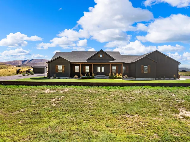 Modern farmhouse-style exterior with dark siding, a covered front porch, and wood-toned accent shutters