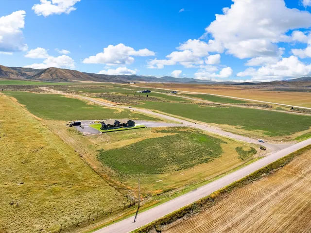 Expansive rural property featuring a main residence, paved driveway, and surrounding agricultural fields