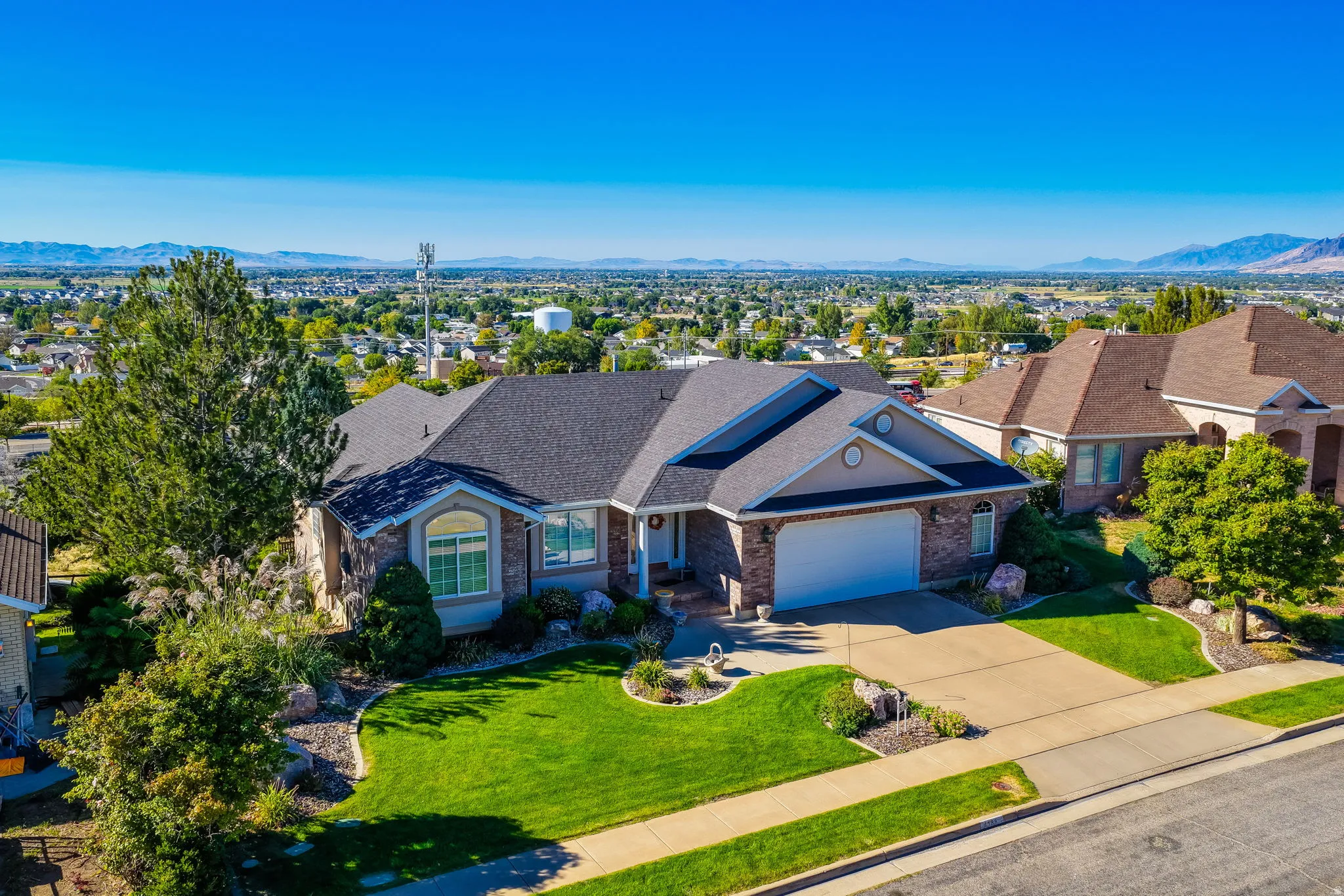 Brick and siding exterior with an attached garage, paved driveway, and manicured landscaping