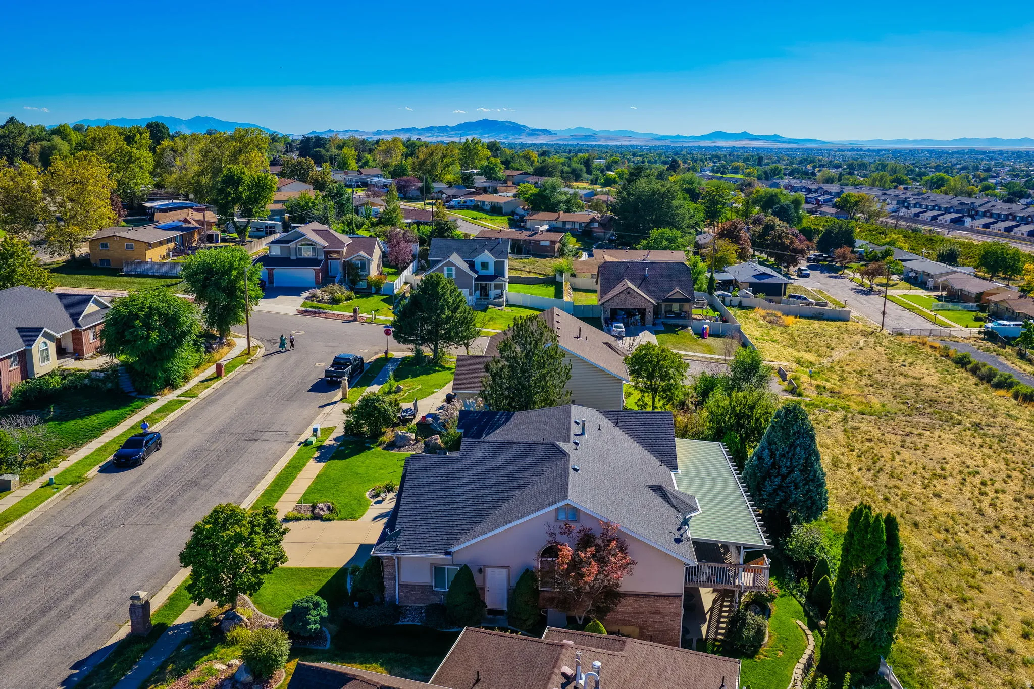 Residential neighborhood with varied architectural styles, mature trees, and mountainous background scenery