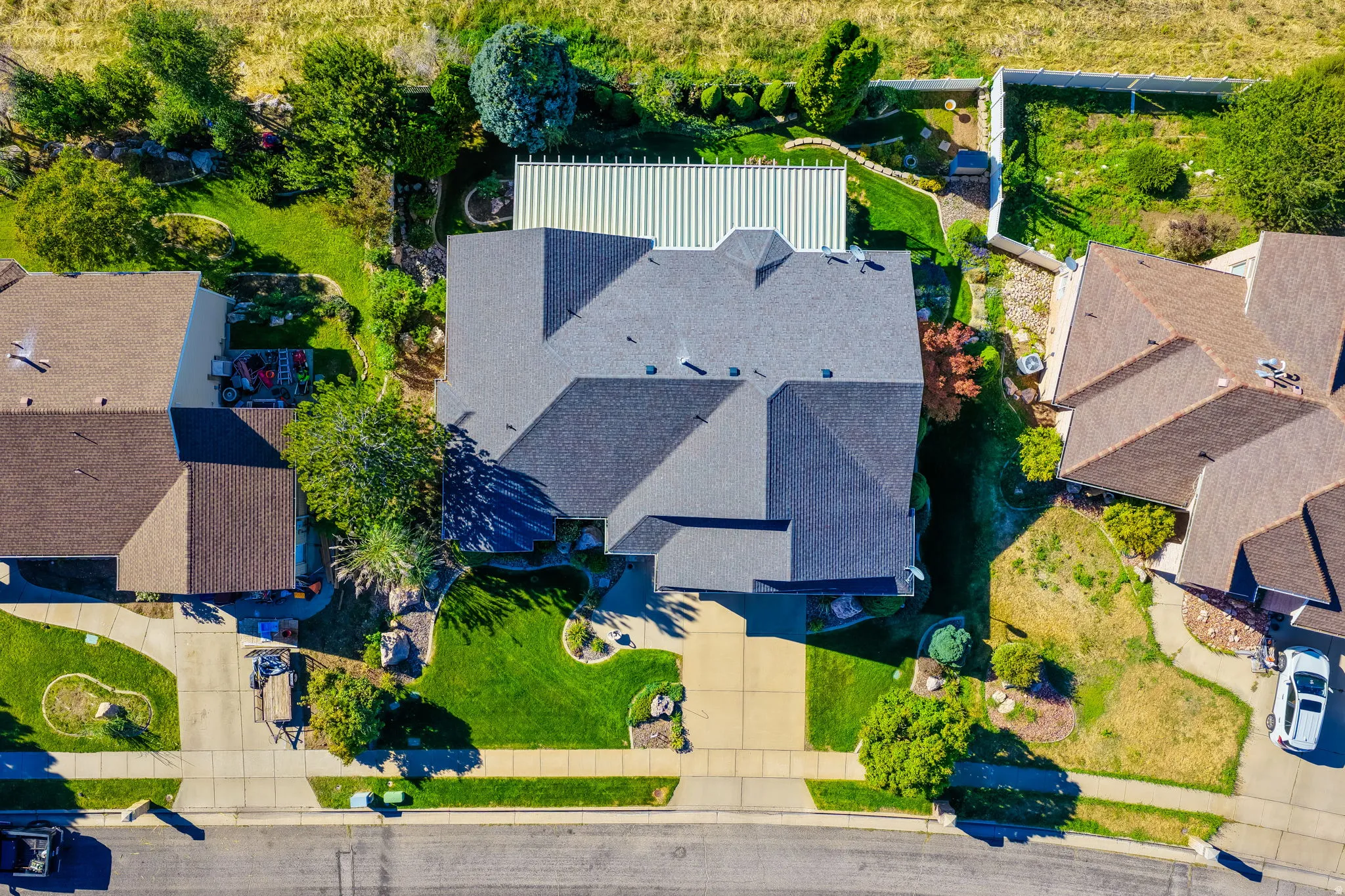 Pitched roofline residence with a front-facing driveway, surrounded by green lawns and mature landscaping