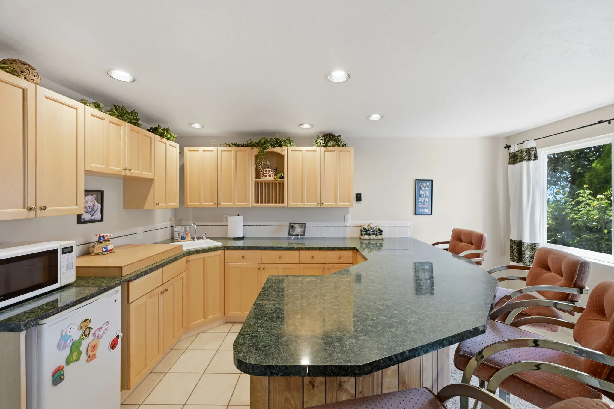 Kitchenette with recessed lighting, wood cabinetry, green speckled countertops, built-in sink, and tile flooring
