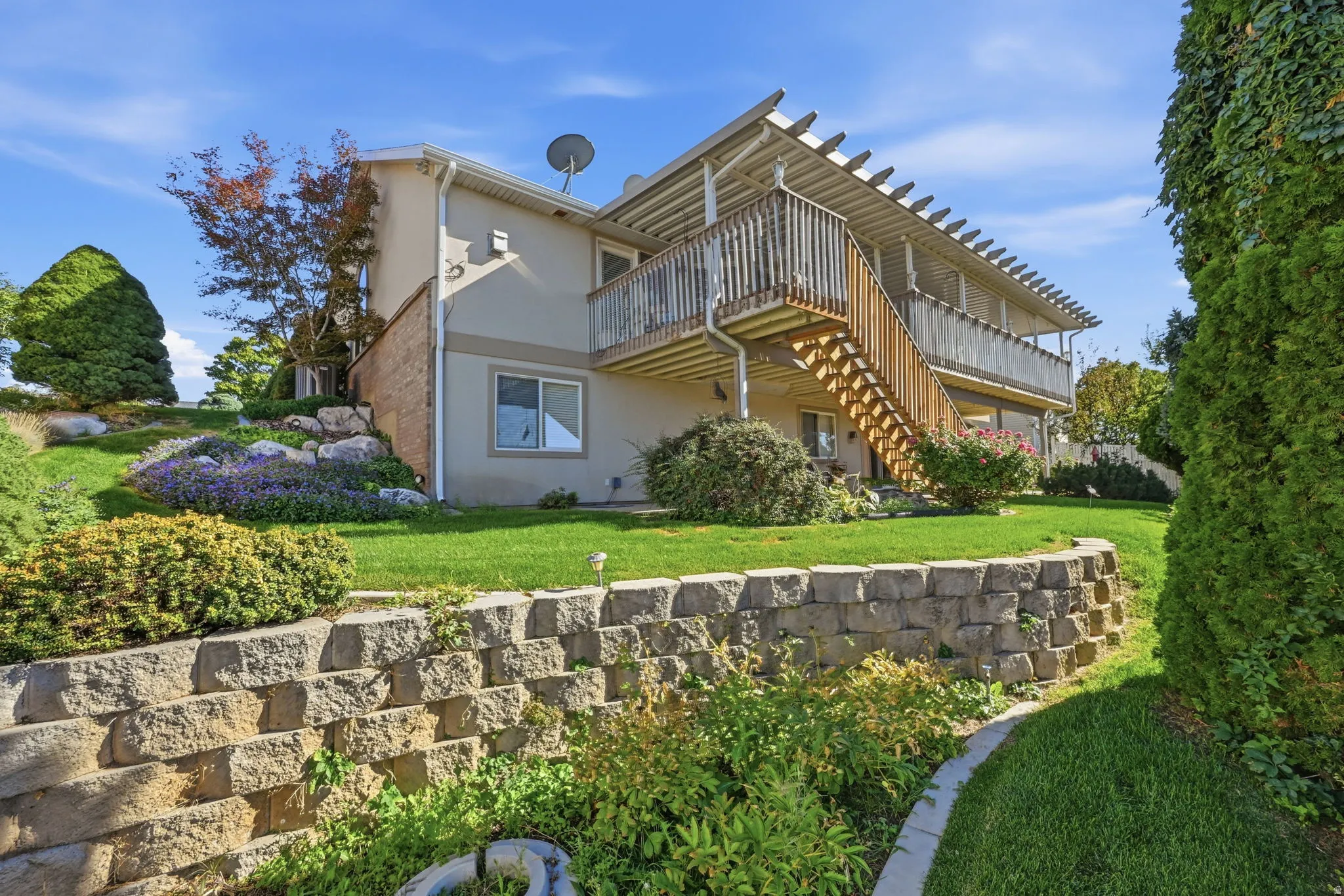 Terraced landscaping with a stone retaining wall, expansive lawn, and mature plantings