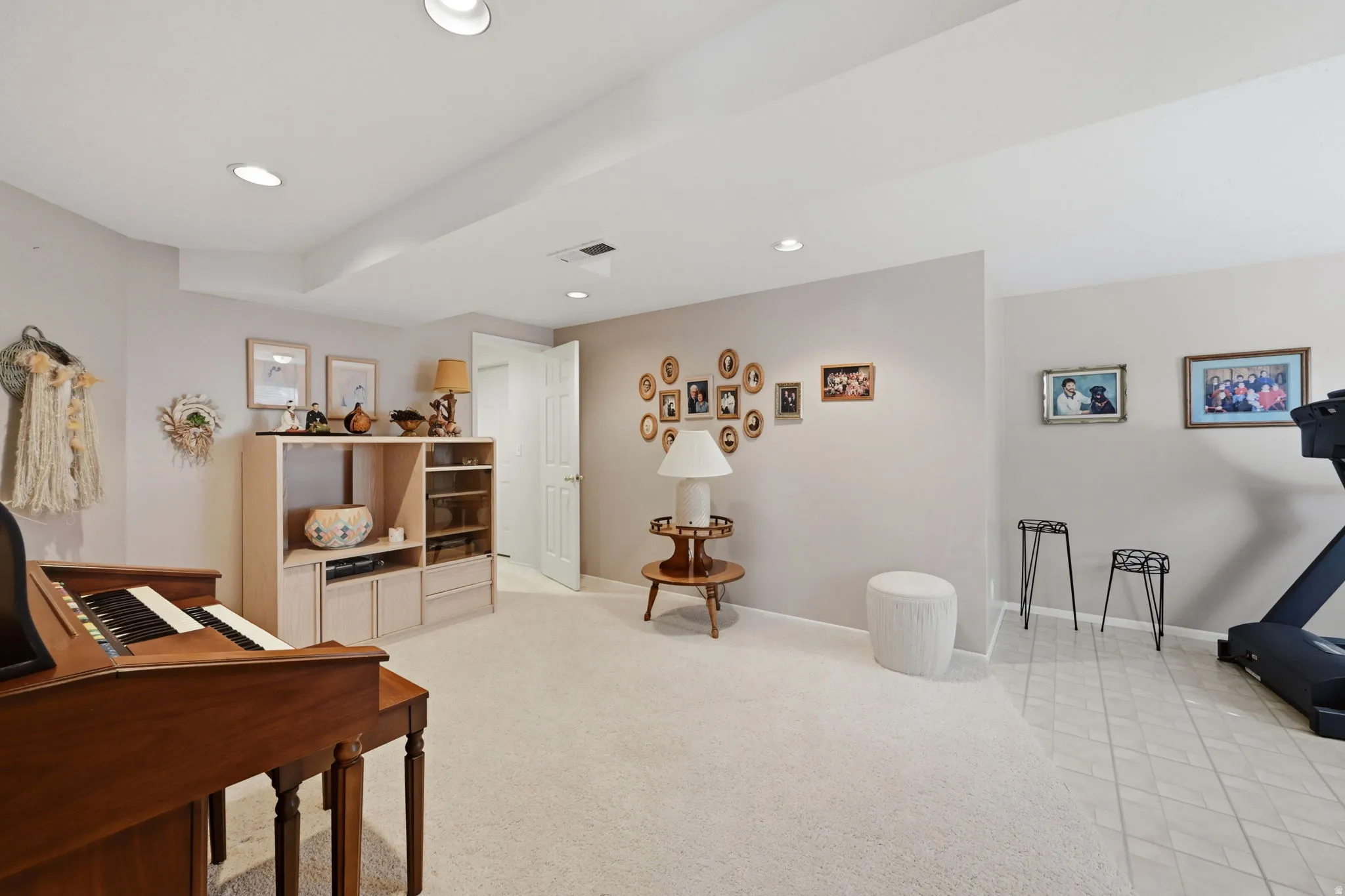 Large bedroom or office/exercise room. Recessed lighting, painted walls, carpeted and vinyl flooring, built-in shelving, and a white paneled door