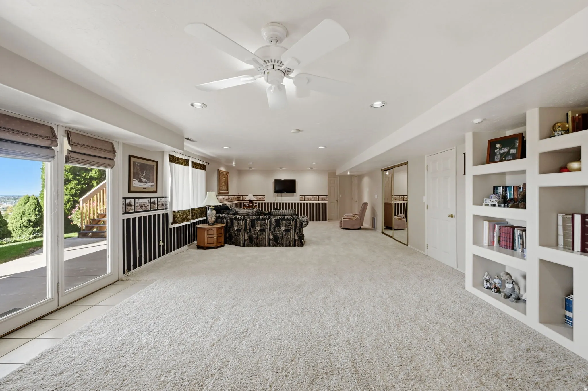 Huge living room, Full-light glass doors, walk out basement, built-in shelving, recessed lighting, ceiling fan, and mirrored closet doors