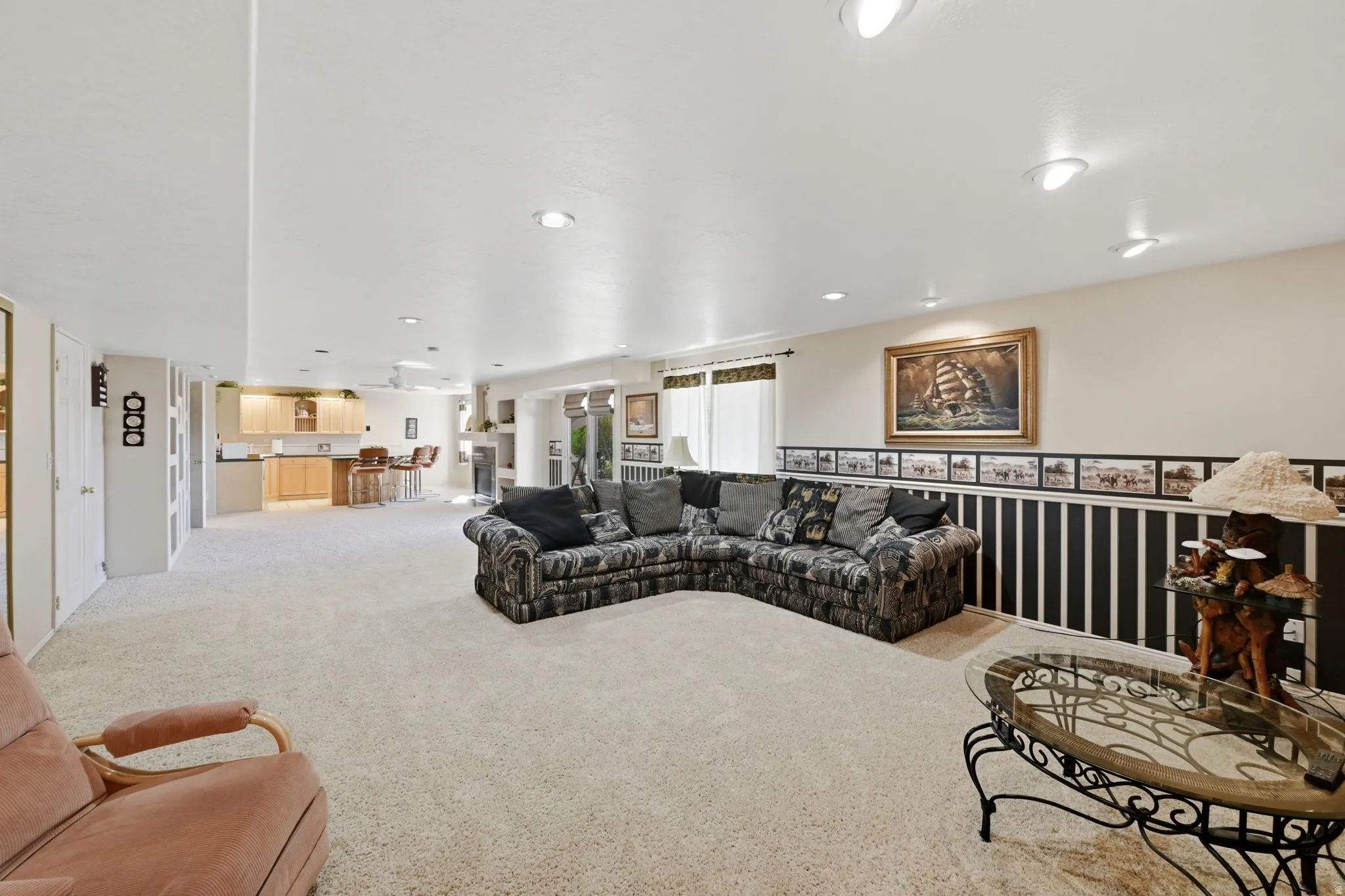 Recessed lighting, light-toned carpeting, and a built-in wet bar with wood-finish cabinetry
