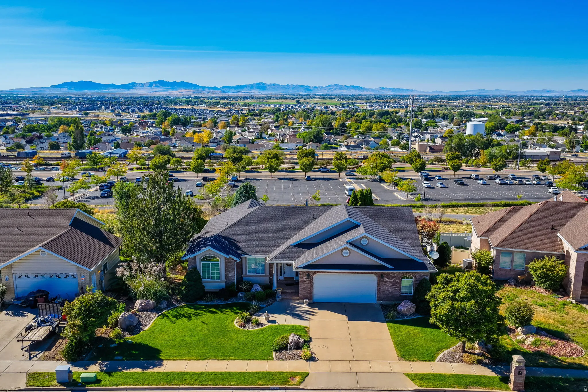 Expansive front lawn with mature landscaping, a two-car garage, beautiful mountain views, and a concrete driveway