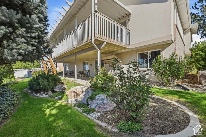 Multi-level exterior with a ground-level patio and an upper-level balcony featuring white railings