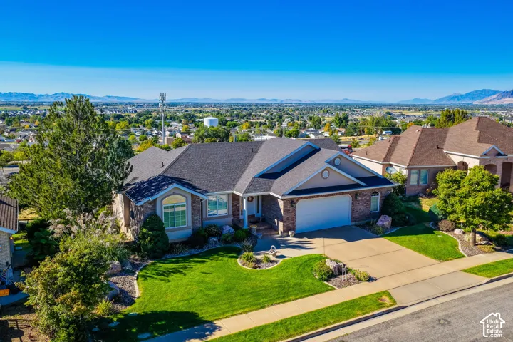 Brick and siding exterior with an attached garage, paved driveway, and manicured landscaping