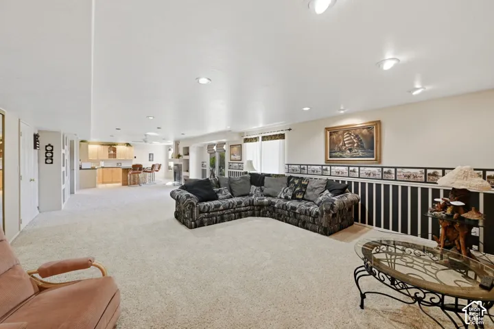 Recessed lighting, light-toned carpeting, and a built-in wet bar with wood-finish cabinetry