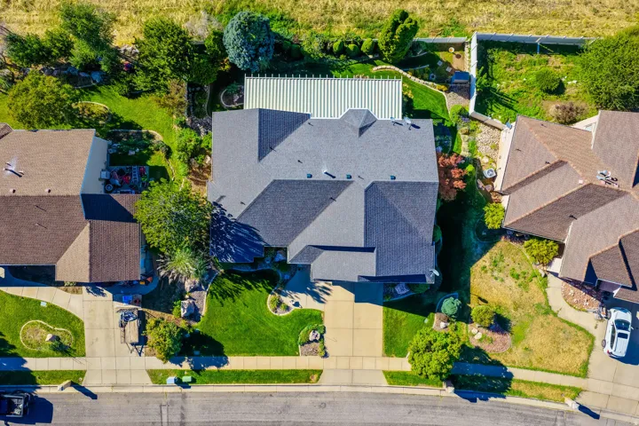 Pitched roofline residence with a front-facing driveway, surrounded by green lawns and mature landscaping