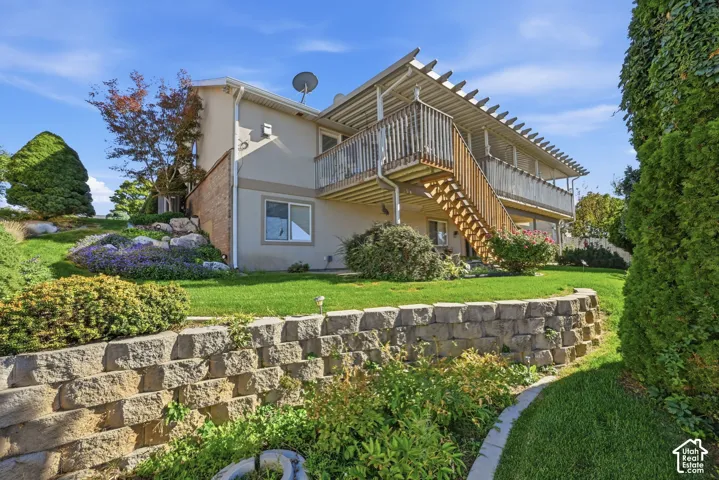 Terraced landscaping with a stone retaining wall, expansive lawn, and mature plantings