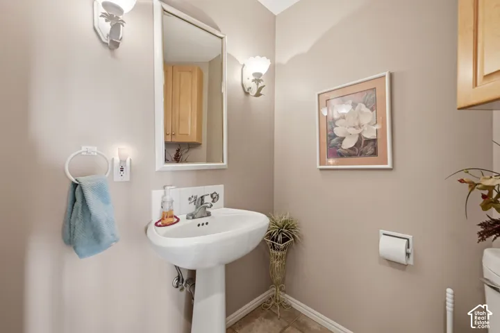 Pedestal sink with chrome faucet, wall-mounted mirror, and decorative wall sconces