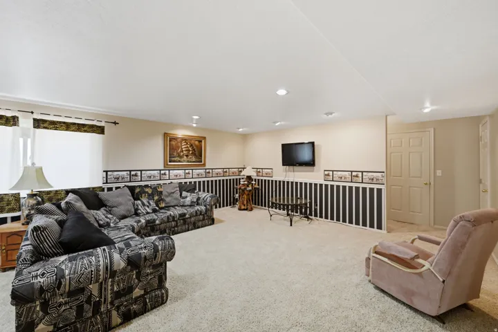 Recessed lighting illuminates a spacious room featuring a window with privacy blinds, beige walls, and a textured ceiling
