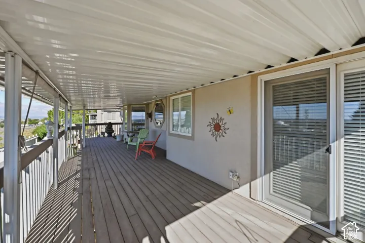 Expansive covered deck with wood-finish flooring, white railing, multiple windows, and sliding doors