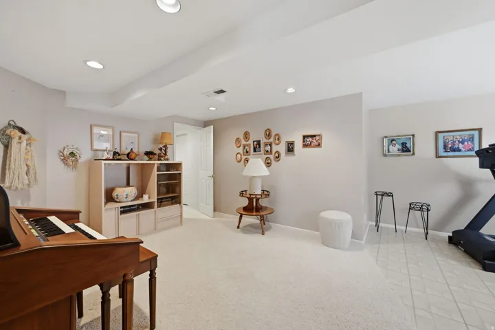 Large bedroom or office/exercise room. Recessed lighting, painted walls, carpeted and vinyl flooring, built-in shelving, and a white paneled door