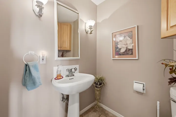 Pedestal sink with chrome faucet, wall-mounted mirror, and decorative wall sconces