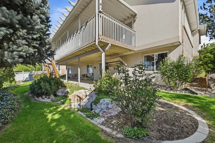 Multi-level exterior with a ground-level patio and an upper-level balcony featuring white railings
