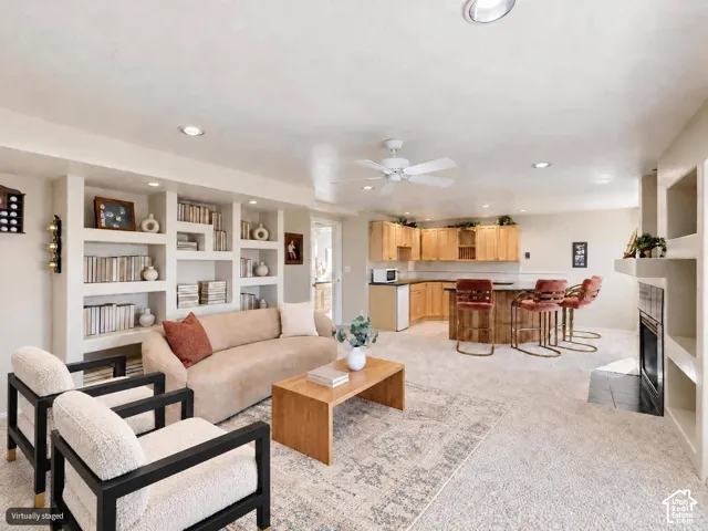 Some digital altered furniture. Open concept living area featuring custom built-in shelving, a fireplace with a decorative surround, recessed lighting, and a ceiling fan