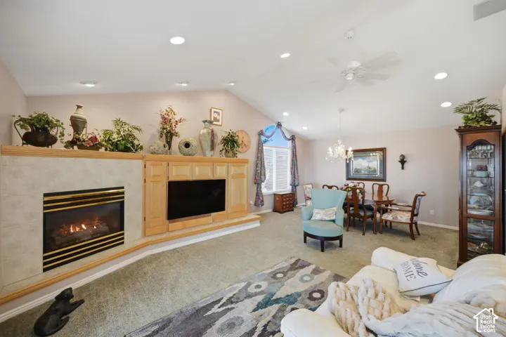 Vaulted ceiling with recessed lighting, built-in fireplace with tile surround, built-in media cabinetry, and dining area with chandelier