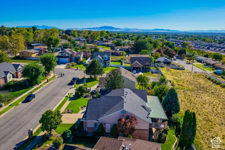 Residential neighborhood with varied architectural styles, mature trees, and mountainous background scenery