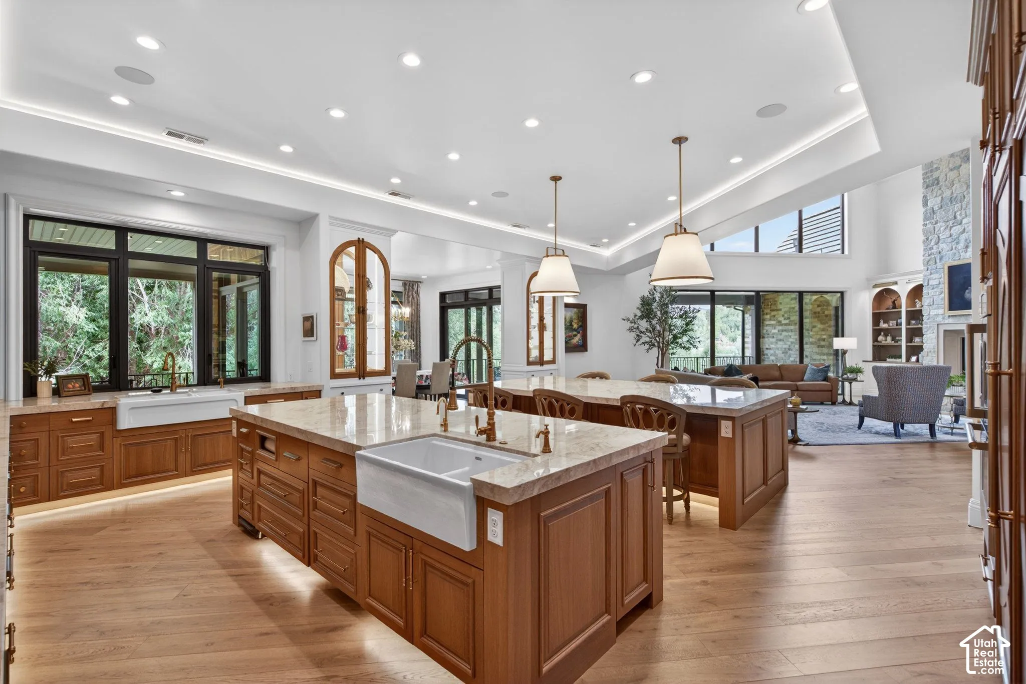 Kitchen featuring two islands with farmhouse sinks, oak wood flooring and large windows