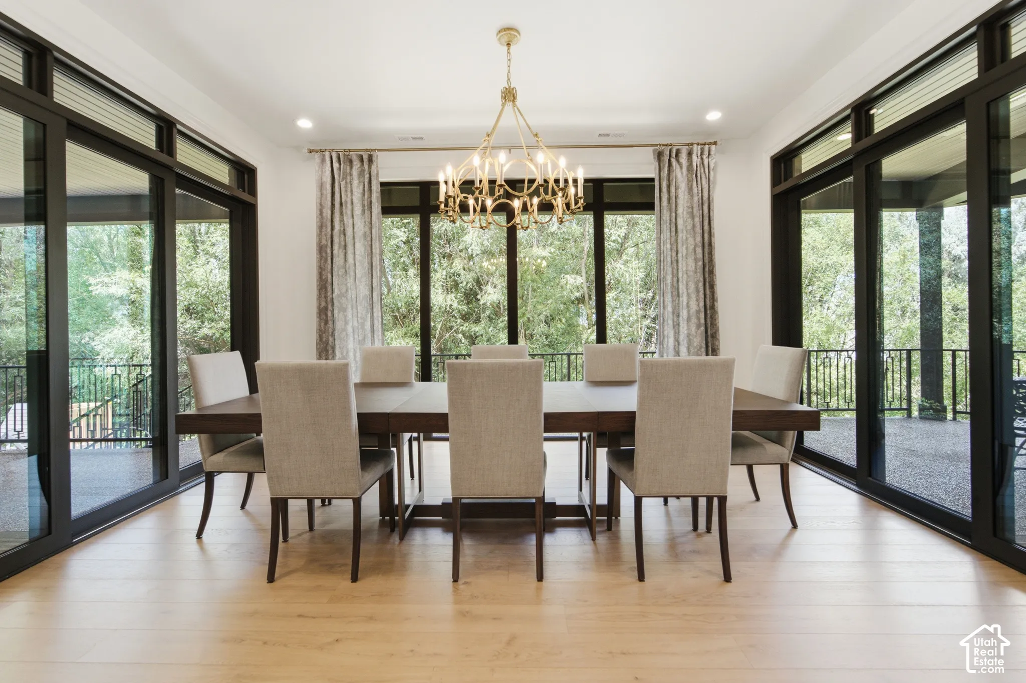Oak wood-finish flooring, gold-tone chandelier, floor to ceiling windows