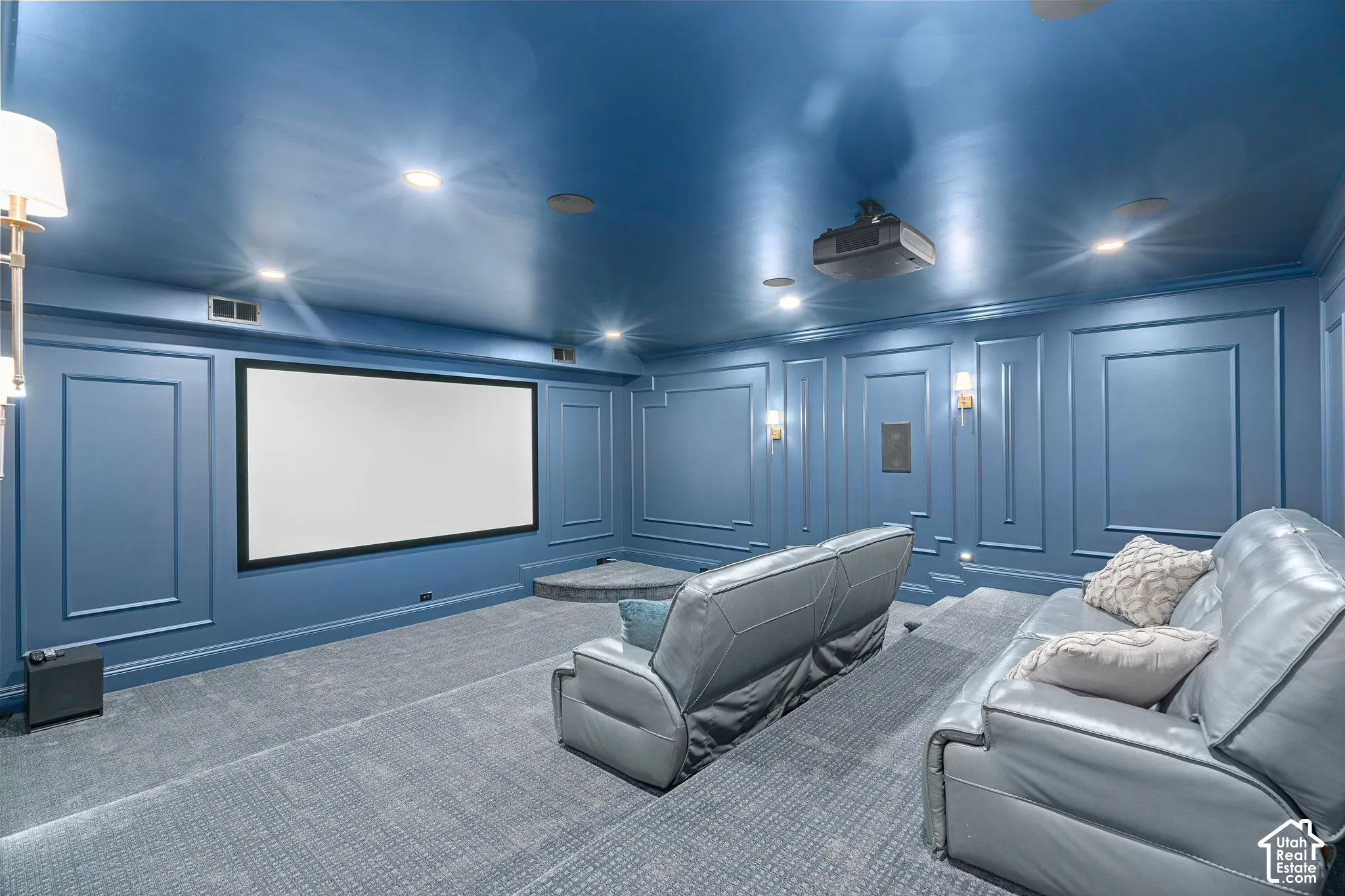 Dedicated media room featuring a large projection screen, recessed lighting, and wall sconces