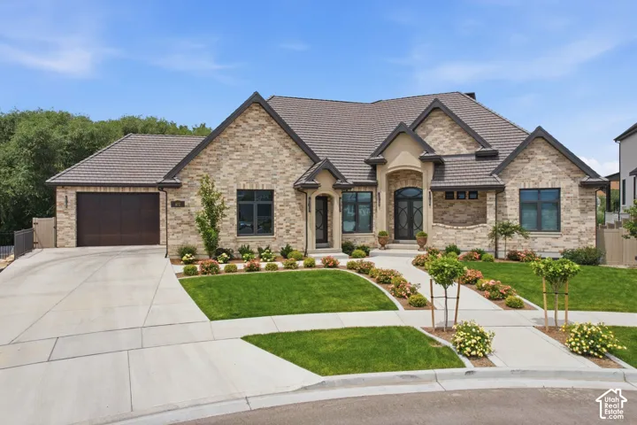Brick with a bar tile roof, an attached 6 car garage, and established landscaping