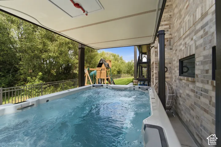 Covered outdoor swim spa with brick exterior and fenced perimeter