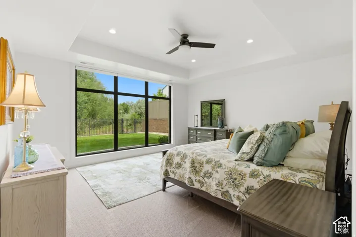 Recessed lighting and a ceiling fan illuminate a tray ceiling