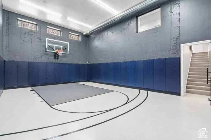 Indoor sports court with high ceilings, recessed lighting, upper windows, and protective wall padding