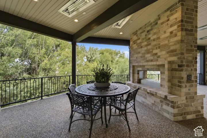 Covered outdoor living space featuring an exposed aggregate floor, brick fireplace with a mantle, view of creek