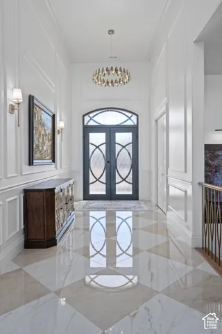 Grand entryway featuring checkerboard-patterned polished tile flooring and decorative wall paneling