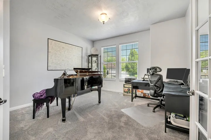 Recessed ceiling light fixture, neutral carpet flooring, double windows with horizontal blinds, and a white paneled door with glass inserts