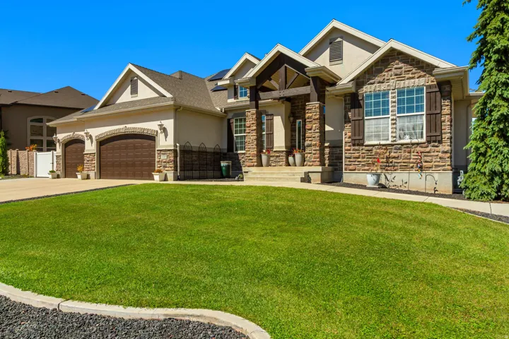 Stone and stucco exterior with multiple gables, arched garage doors, and a covered entry