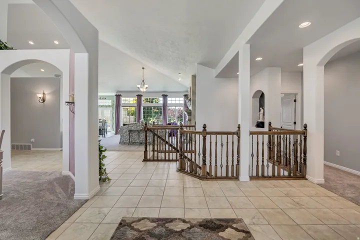 Tiled entryway featuring a wood spindle railing, arched doorways, and recessed lighting