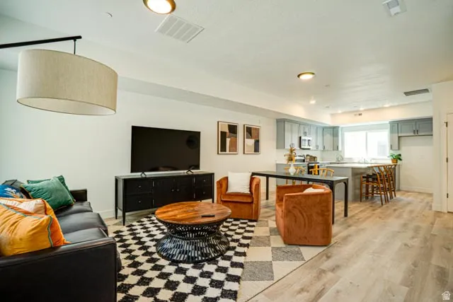 Open-concept living area with wood-finish flooring, recessed lighting, and a drum pendant light fixture