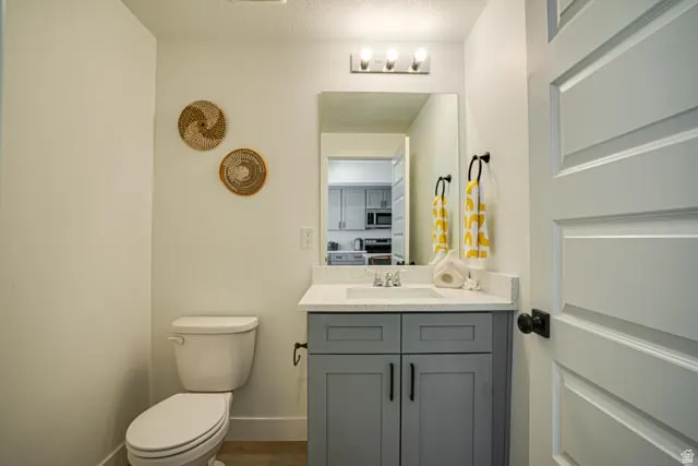 Vanity with a light-colored countertop, wall-mounted mirror, and a three-light fixture