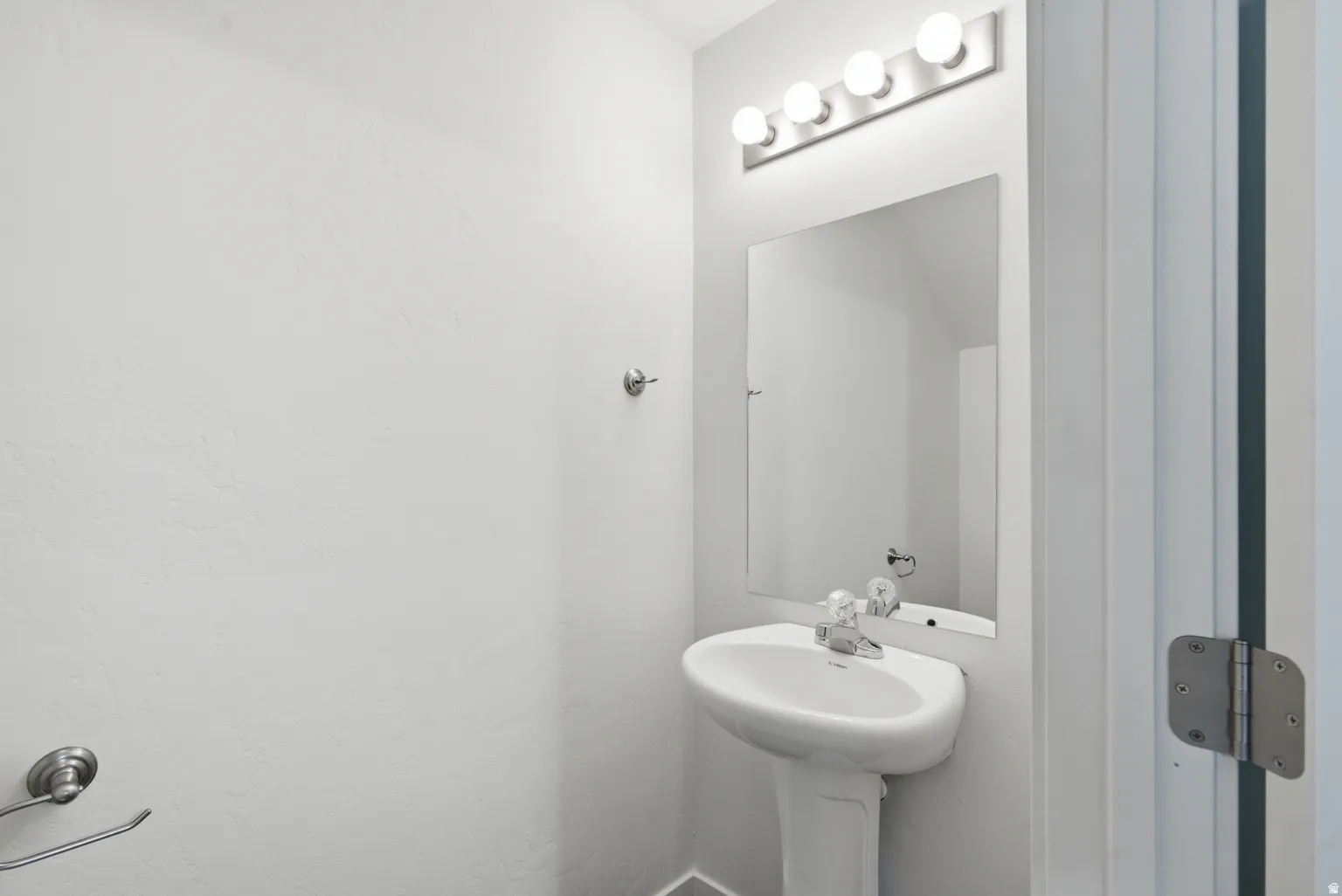 Pedestal sink with chrome faucet, large vanity mirror, and overhead light fixture