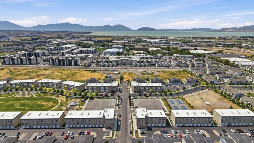Expansive aerial perspective showcasing a developed community with multi-story residential buildings, ample surface parking, and a prominent mountain range backdrop