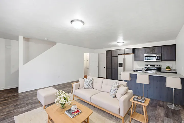 Wood-finish flooring throughout, with a kitchen featuring dark wood cabinetry, stainless steel appliances, and a breakfast bar