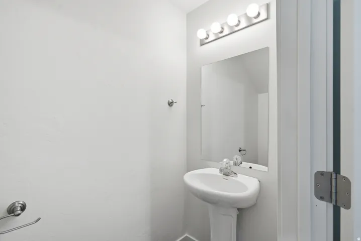 Pedestal sink with chrome faucet, large vanity mirror, and overhead light fixture