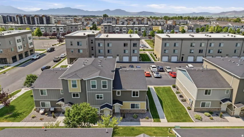 Contemporary townhome architecture featuring varied siding textures, private front entries, landscaped front yards with mature plantings, and a paved parking area