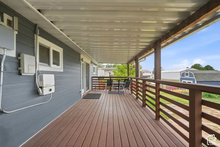 Expansive covered deck featuring wood-finish flooring and a wood railing