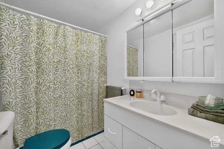 White vanity with integrated sink, three-door mirrored medicine cabinet, and overhead lighting fixture