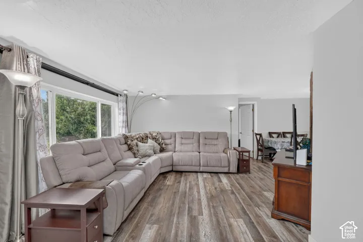 Expansive living area with wood-finish flooring, large windows, and a neutral color palette
