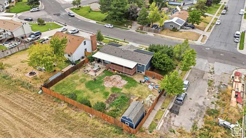 Expansive fenced backyard featuring a grassy area, mature trees, and a storage shed
