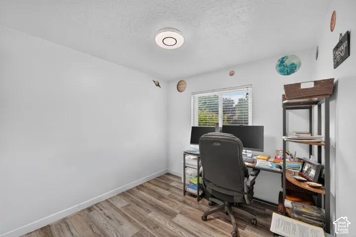 White walls, wood-finish flooring, and a ceiling-mounted light fixture