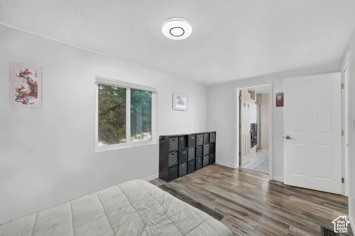 Room featuring wood-finish flooring, a neutral color palette, a sliding window, and a circular flush-mount ceiling light fixture